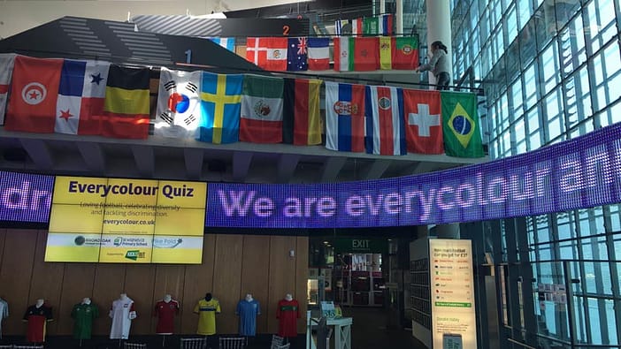 View of the museum atrium with the animated Everycolour slogan on the moving sign with the flags form all the Wolrd Cup nations hanging above.