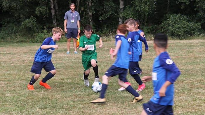 Players from Broad Oak surround a forward from St Wilfrid's CE as he dribbles past them all